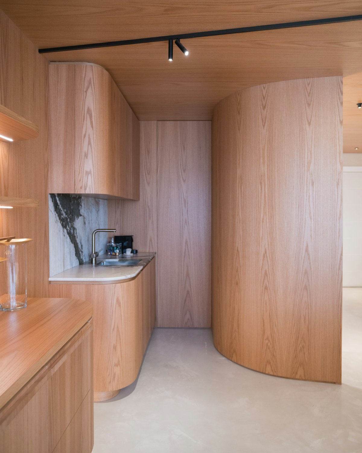 Curved oak joinery and stone benchtop inside a Deol Build residence